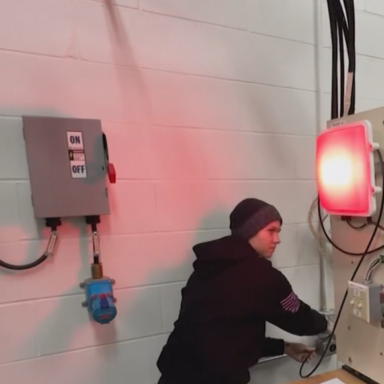 Kelsey Johannsen testing electrical connections. MELTRIC receptacle is in the background of the image.